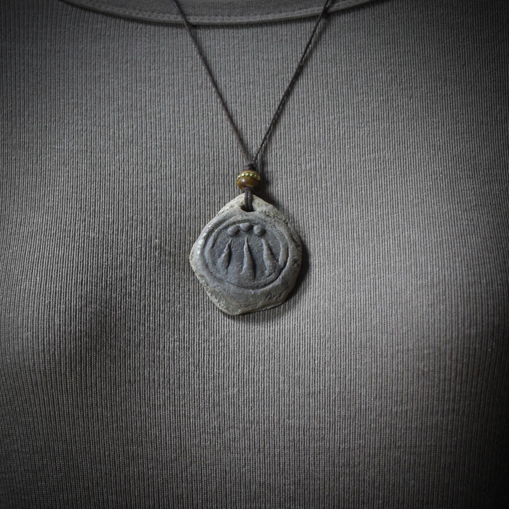 Handgefertigter Awen-Anhänger aus traditionell gebranntem Ton mit rustikalem Leder- oder Baumwollband